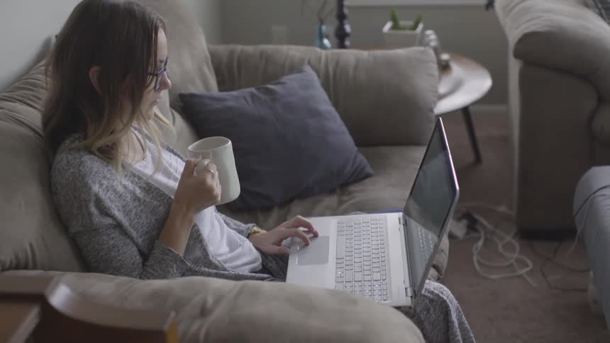 Woman works on her laptop while sitting on the couch