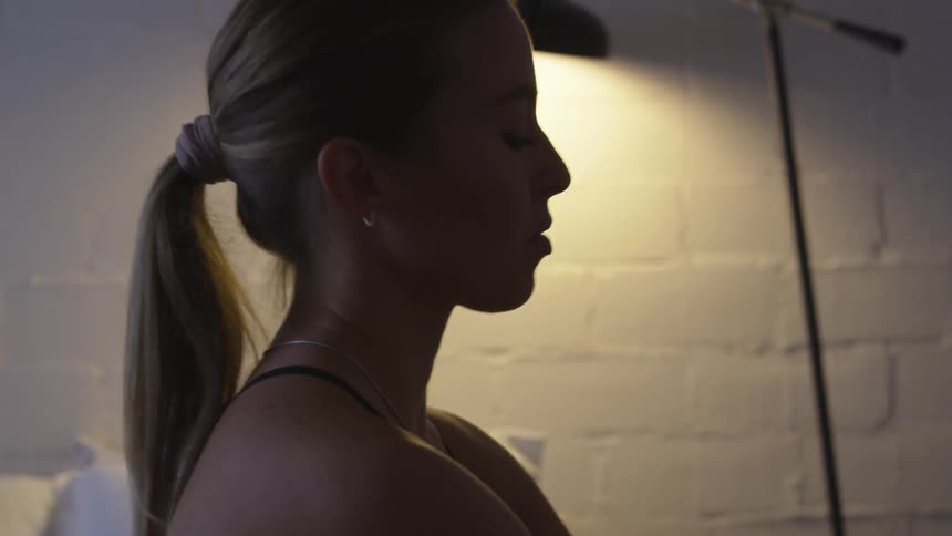 White woman getting up from bed and stretching her neck