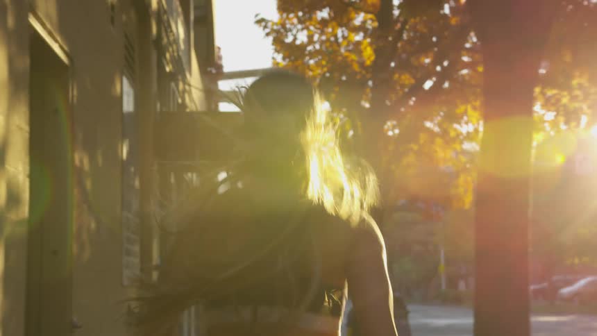 A woman runs down a sidewalk in the city