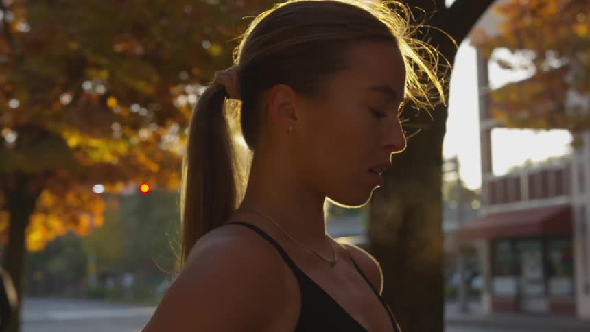 Woman catching up her breath at sunrise next to a street