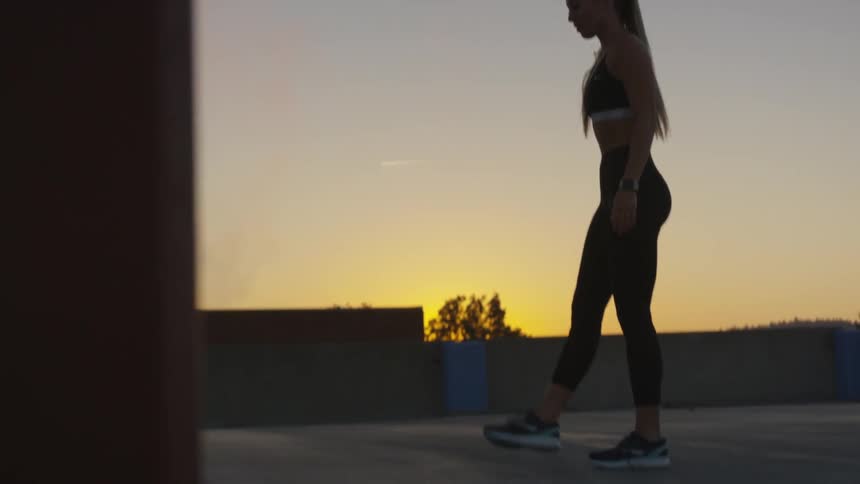 A young white woman in workout attire bends and touches the ground