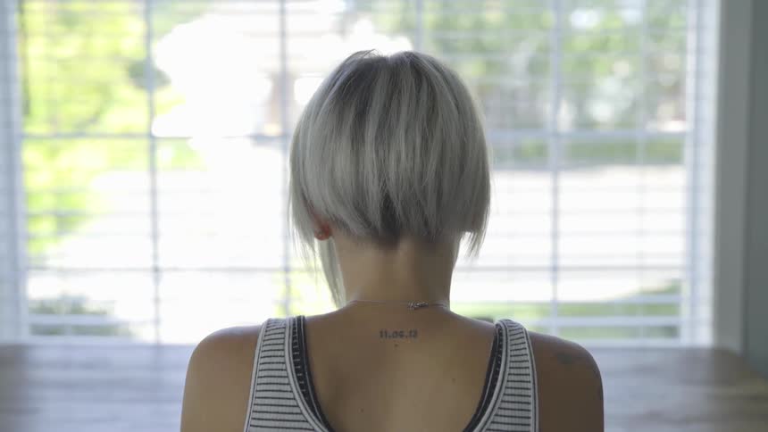 Short haired woman reading at a table facing a window