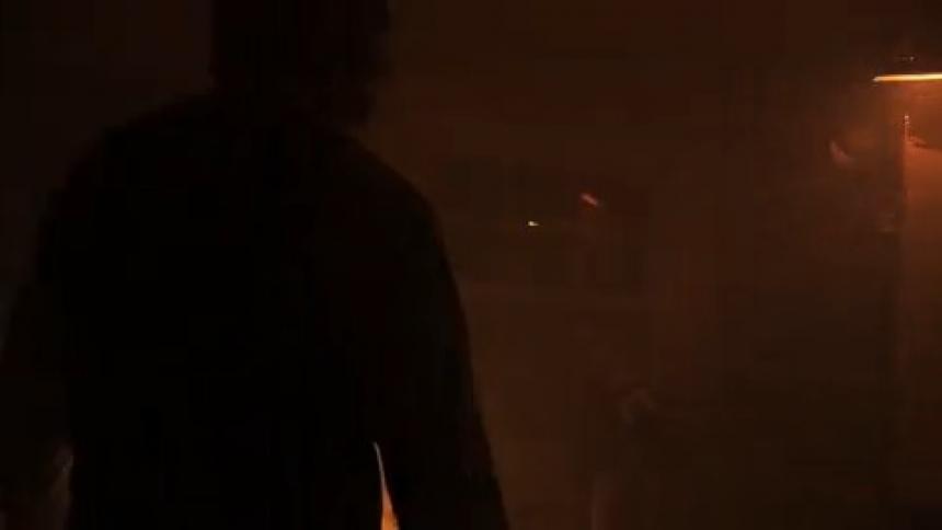 A silhouetted man stands in front of a flashing lamp