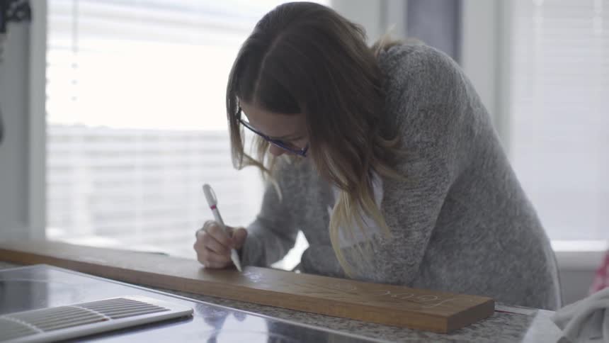 A woman draws on a wood board