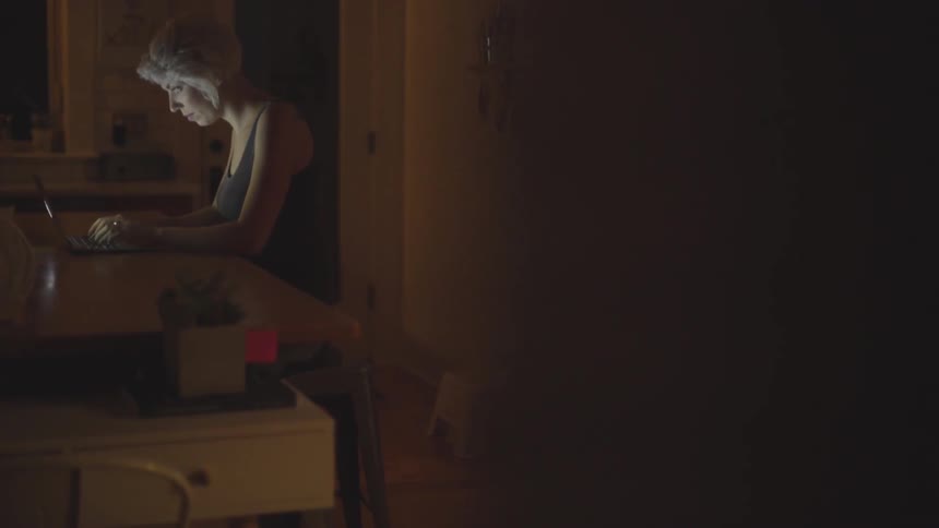 Woman using her laptop on the kitchen counter at night