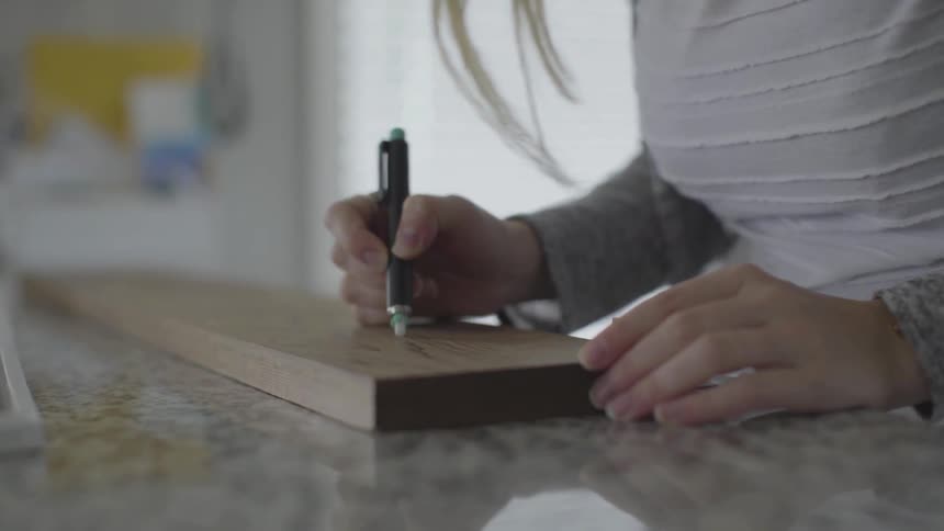 A woman drawing on a wood plank