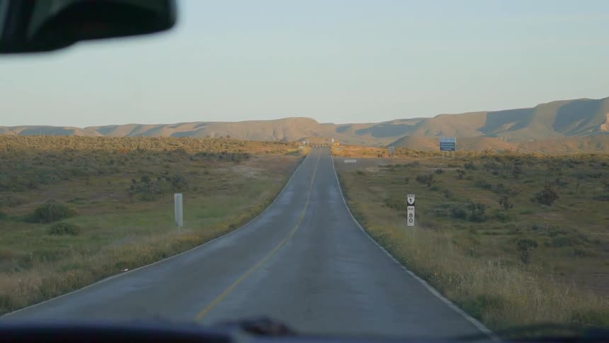 A car drives down a road in a remote area