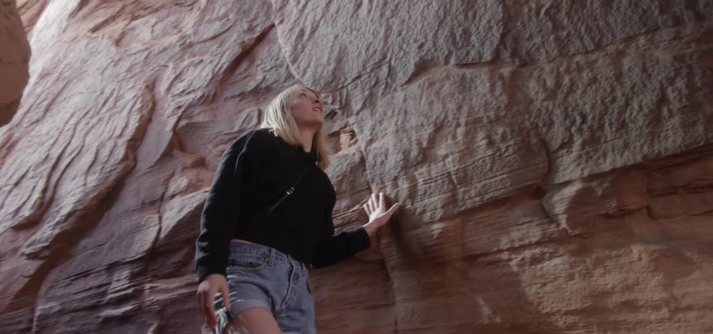 The young girl is climbing down the rocks