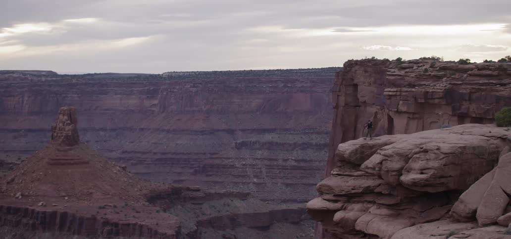 A person walking towards the edge of a canyon