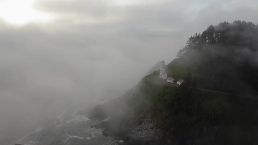 The fog it crawling up the shore covering the lighthouse
