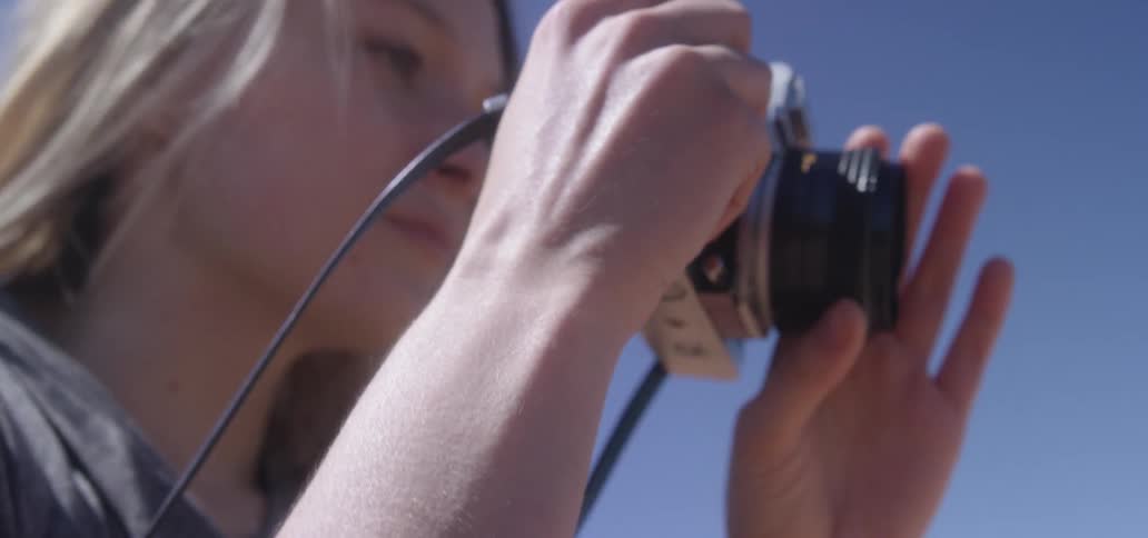 A woman is holding a camera outdoors
