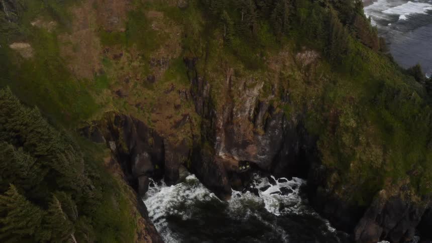 A cliff near the water has waves crashing against it