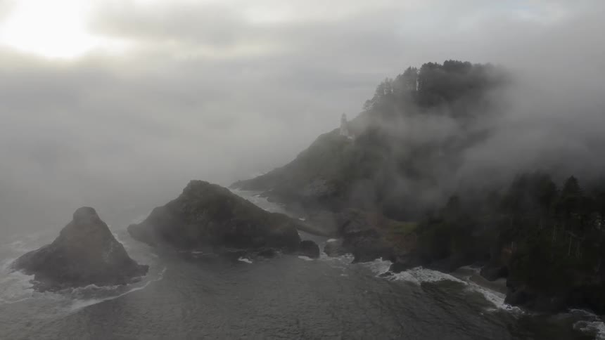Mist and fog rise above the ocean and cliffs