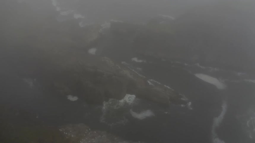 Lighthouse spins light around in fog next to the ocean on a cliff
