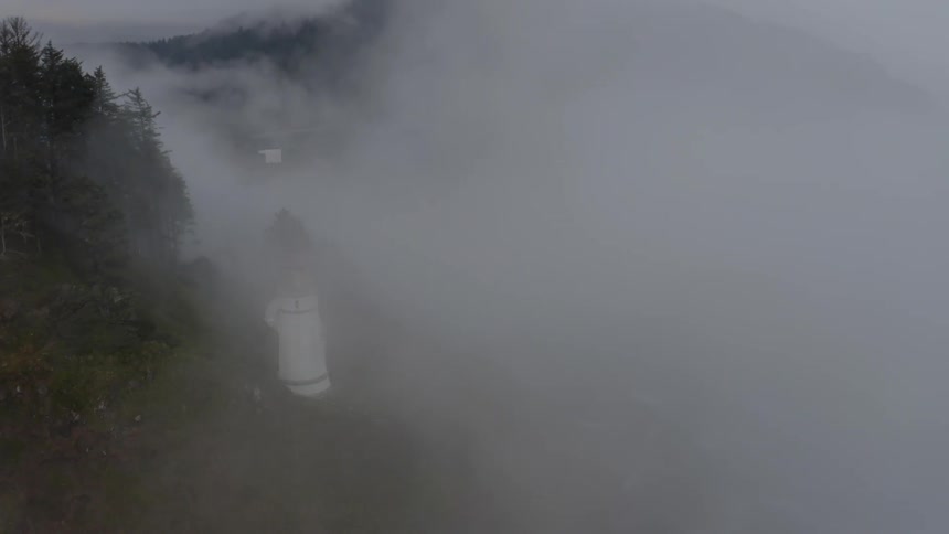 Fog fills valley between mountains near lighthouse