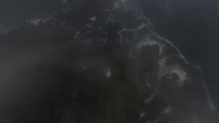 Lighthouse on island surrounded by fog and ocean