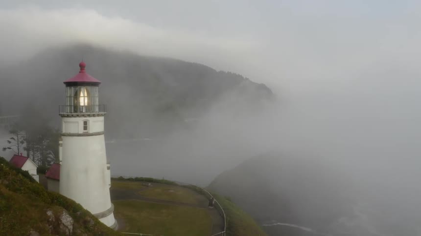 The lighthouse slowly blinks its welcoming light as the mist from below slowly rises to surround it