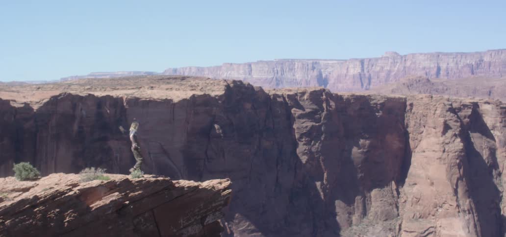 A hiker stops to take a photo of a canyon in a desert