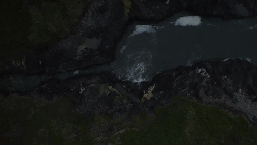 Ocean water flows through a narrow passage and breaks against the rocks