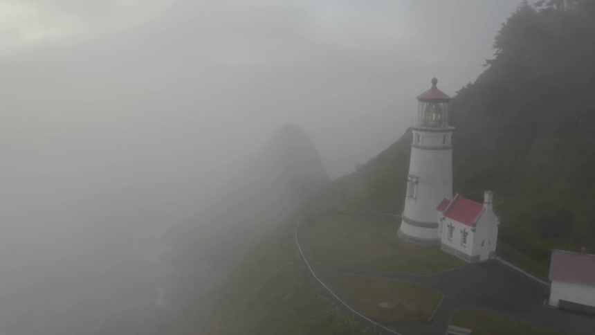 Lighthouse and outbuildings on island cliff in heavy fog