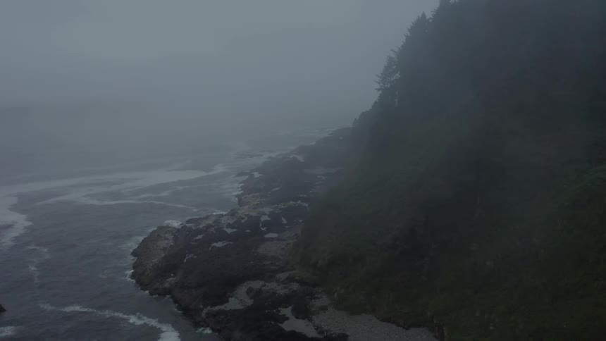 The waves are crashing on the foggy shore of the island