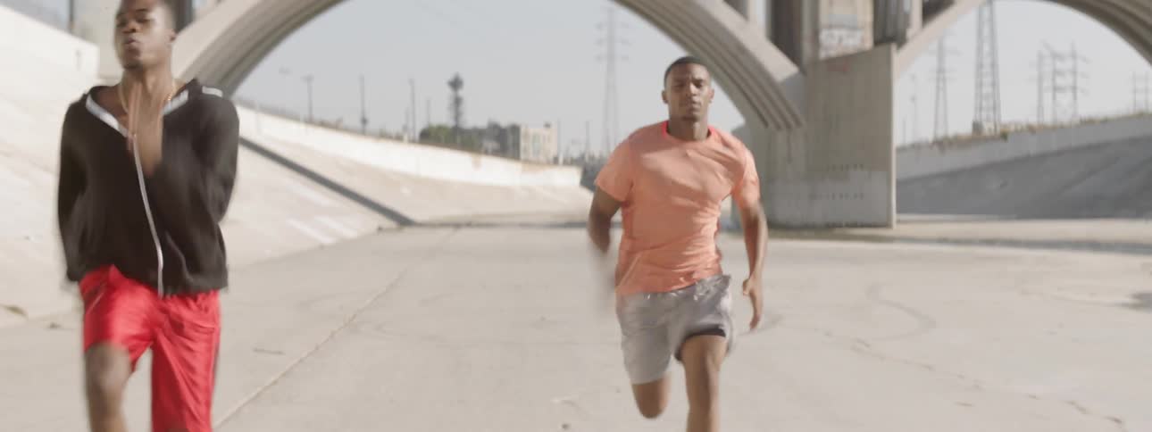 Three men racing through a culvert under a bridge