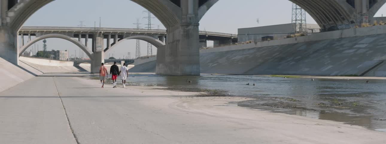 Three black men walk next to the los angeles river