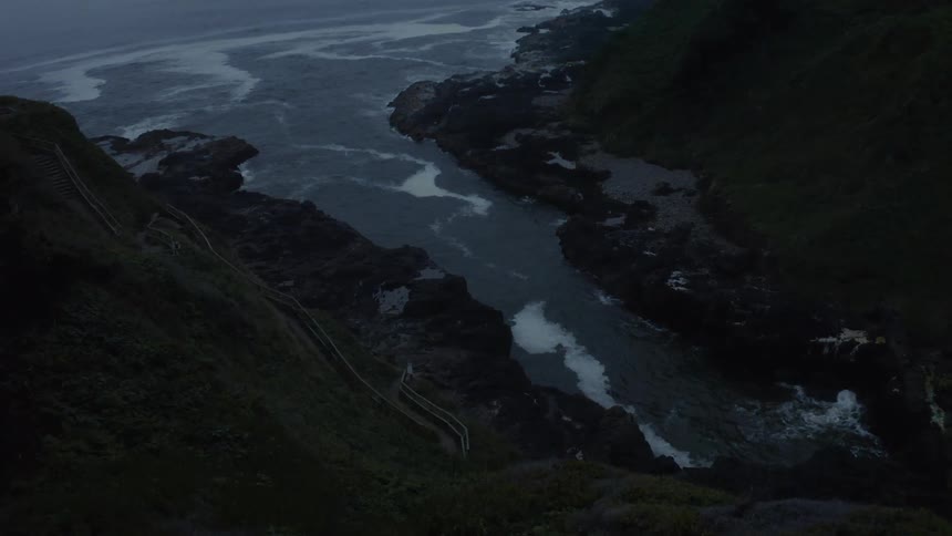 The camera looks down to a rugged coastline