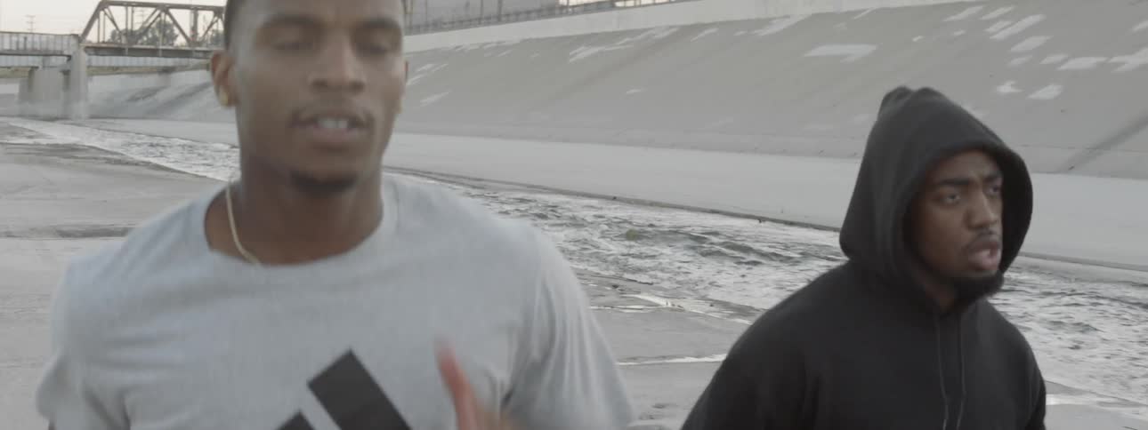 Three black men run along the los angeles river