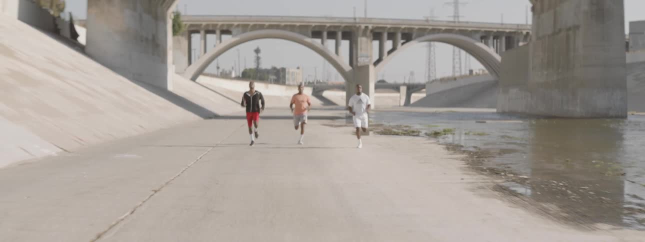 Male runners running through a wash in the city