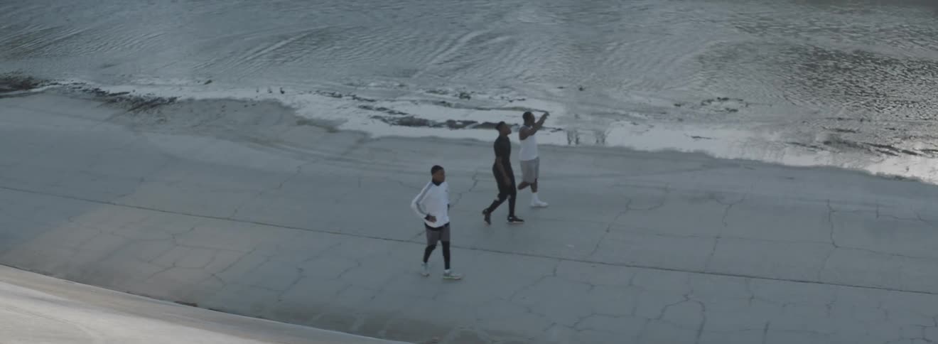 Three men walk on the road near water