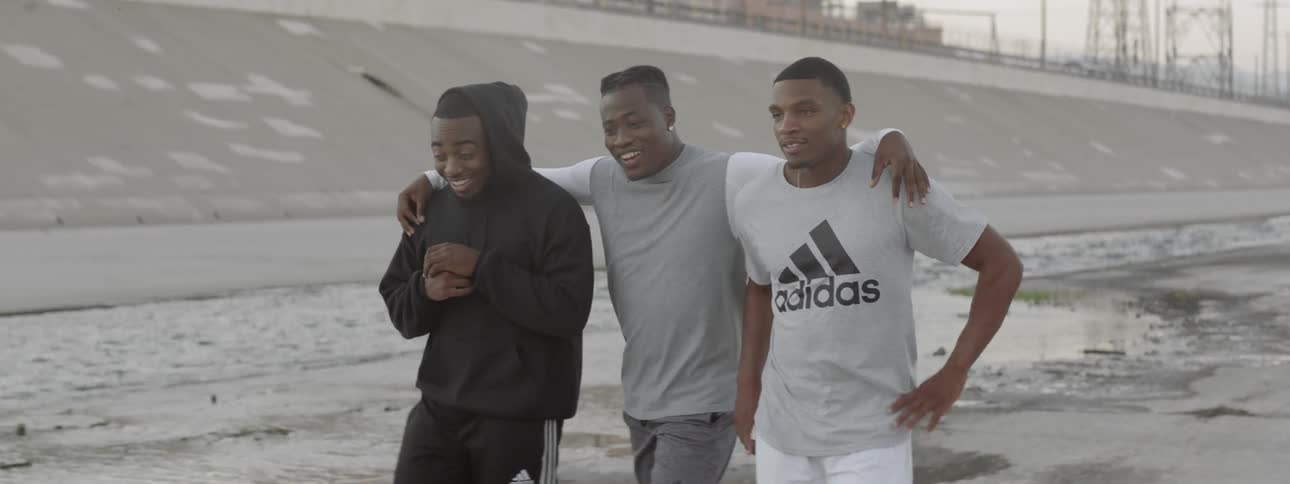 Three young black men walking along a stream of water