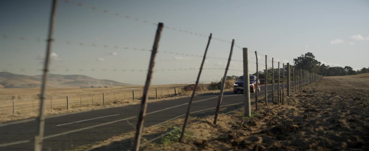 A vehicle drives down a rural road
