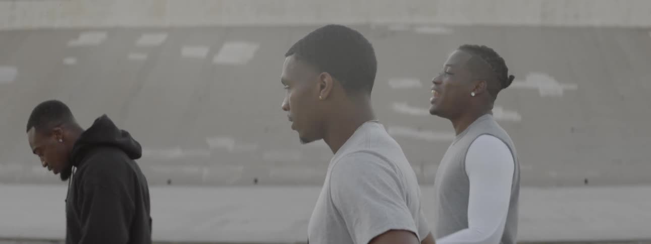 Three black men are walking down in the concrete waterways such as in los angeles
