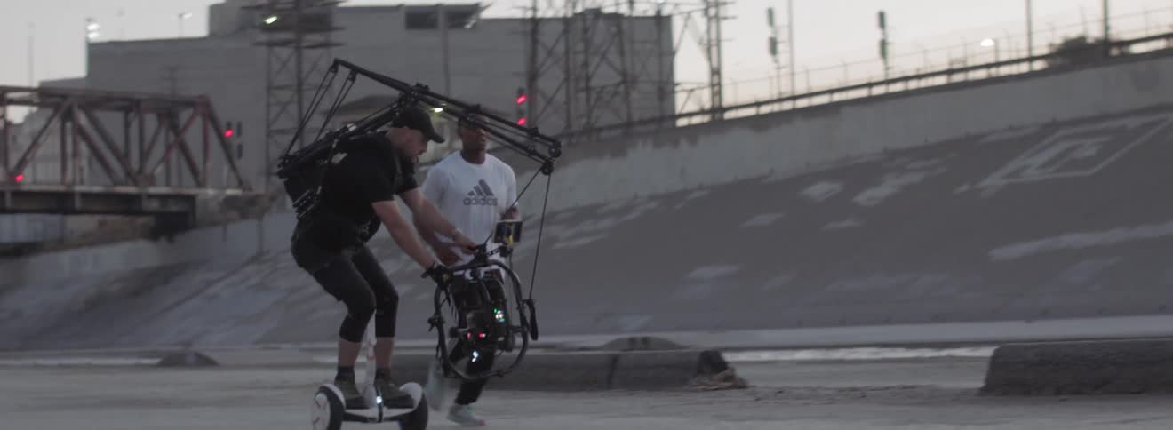 A man using a hoverboard to film a man running