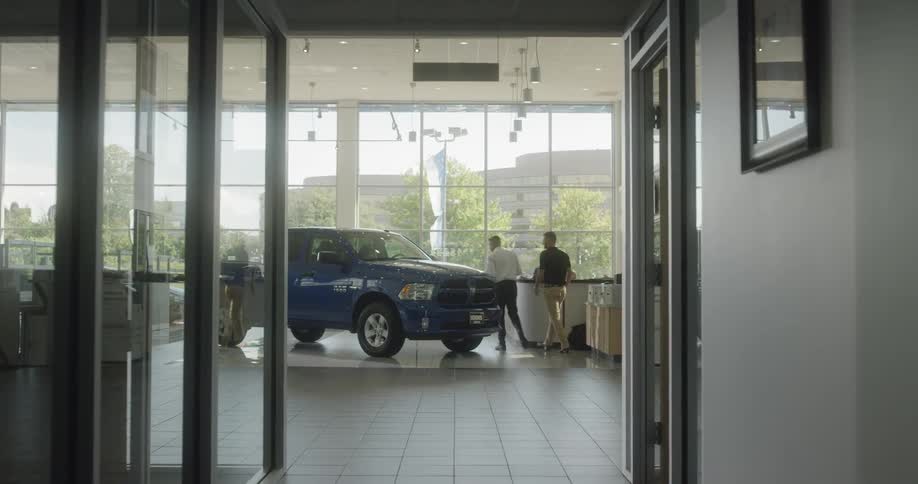 A salesman talking to a customer on a car dealership