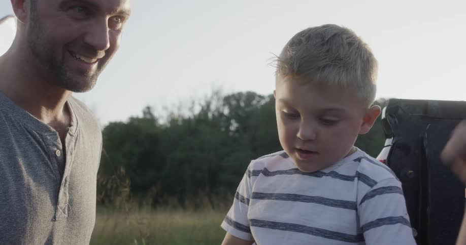 Father and sons laugh and play in field