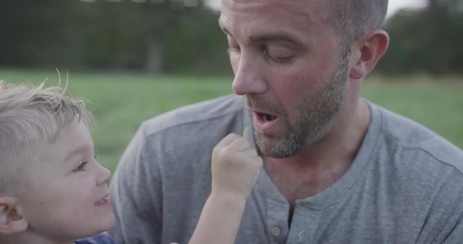 Child holds up blade of grass to father to on it