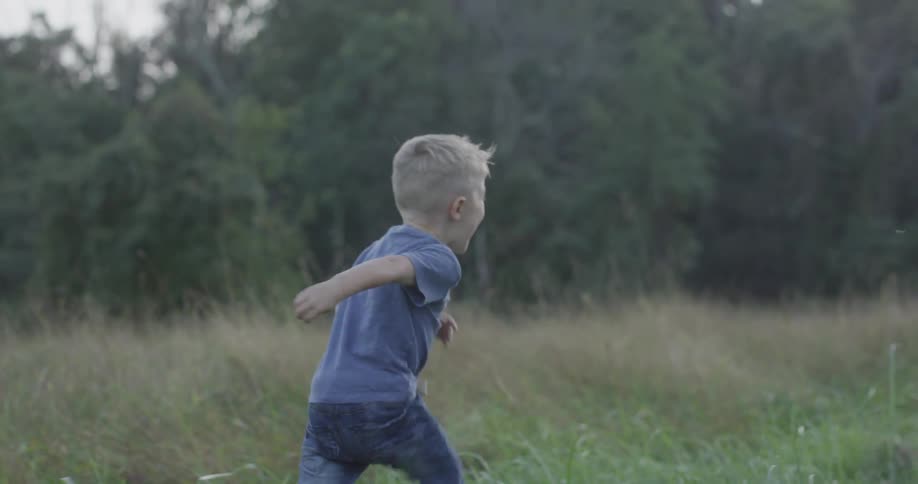 A young boy running through a grassy field