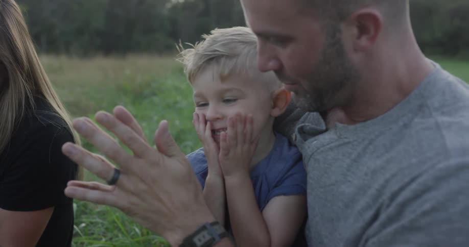 Father holds his son and claps his hands together