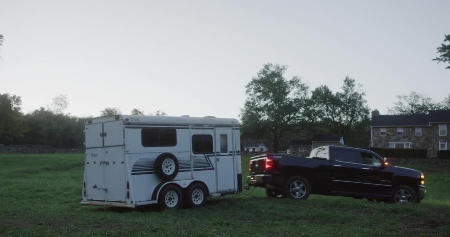 A pickup truck pulls a trailer on a grass field
