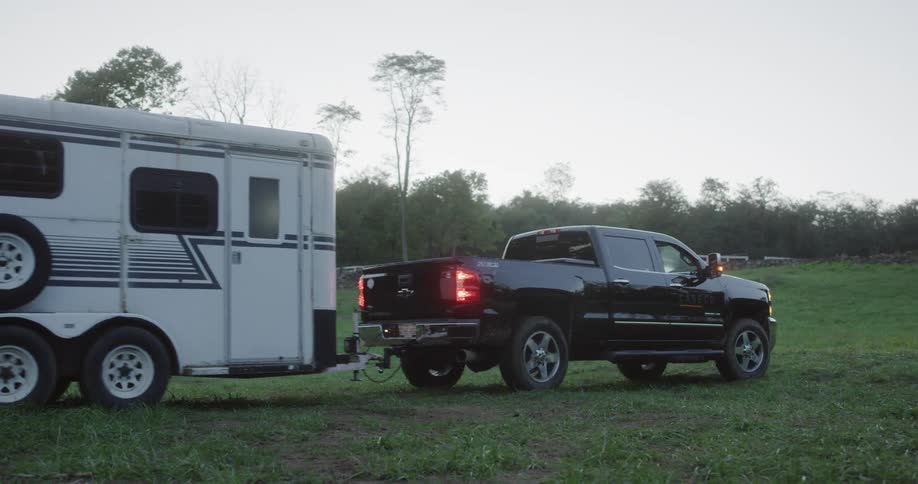 A car is moving a trailer in the grass