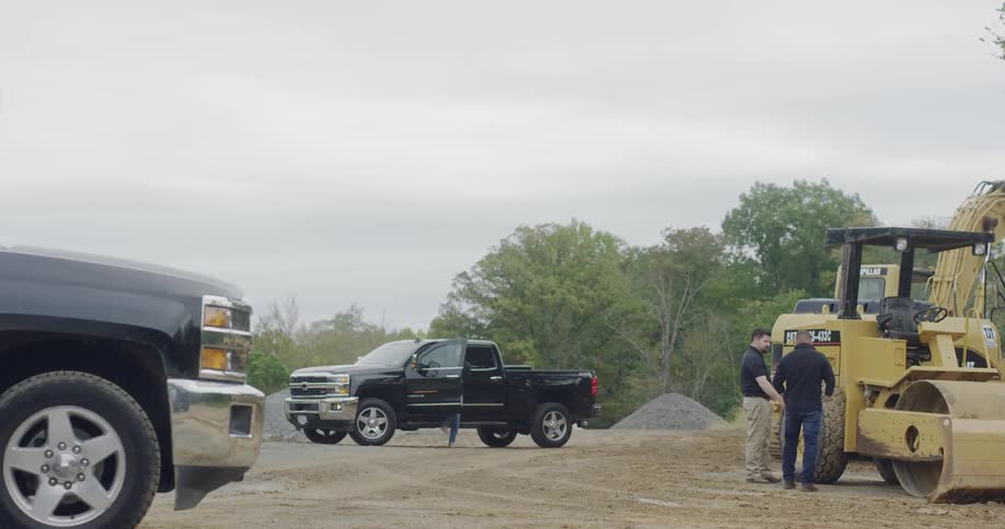 A black car approaches to the excavation site on a cloudy day