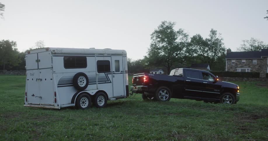 A truck with a trailer backs into a lawn