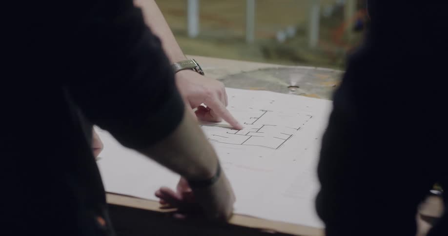 People look at a blueprint drawing on a table