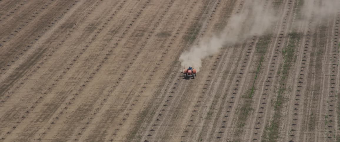 A person drives a red tractor through a farm field