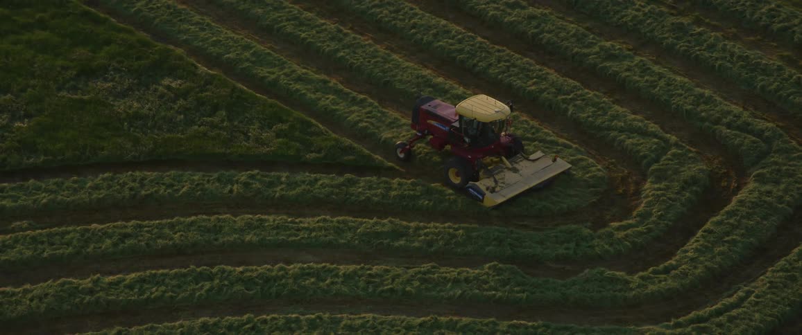 Red tractor drives through large field on farm