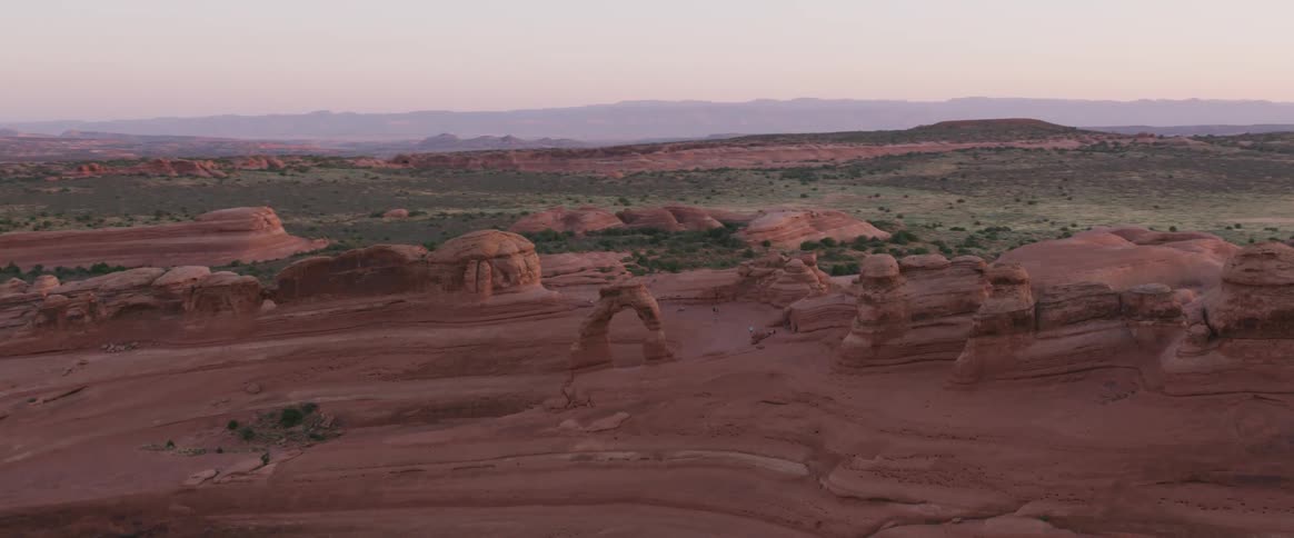 Red rock formations stand in a desert at dawn