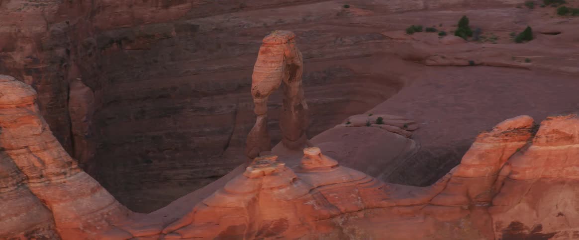A strange rock formation rises up from a red colored plateau