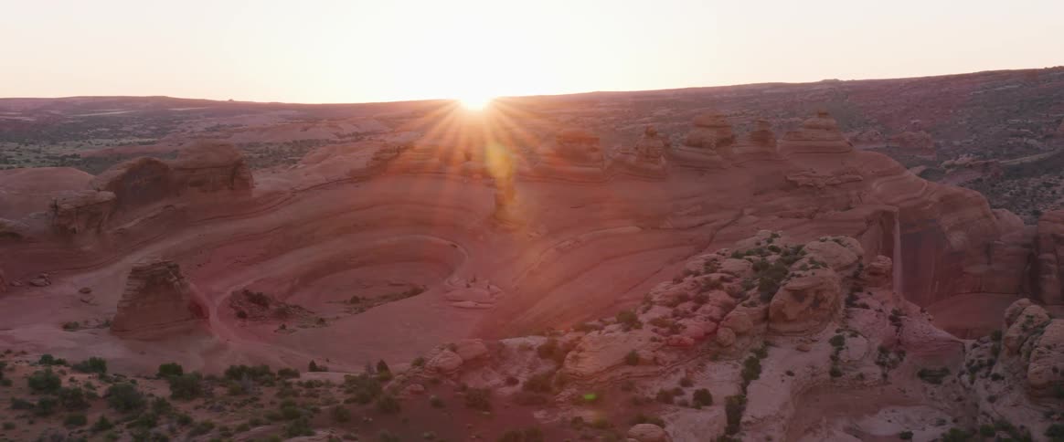The sun shines down on a desert with rose colored plateaus